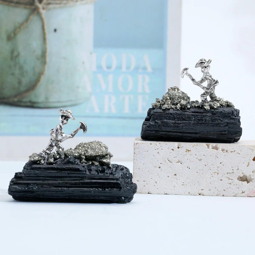 Raw black tourmaline specimen with a metal miner figure, featuring grounding columnar growth for root chakra protection.
