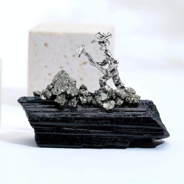 Raw black tourmaline crystal specimen featuring a metal miner figure for grounding, protection, and root chakra healing.