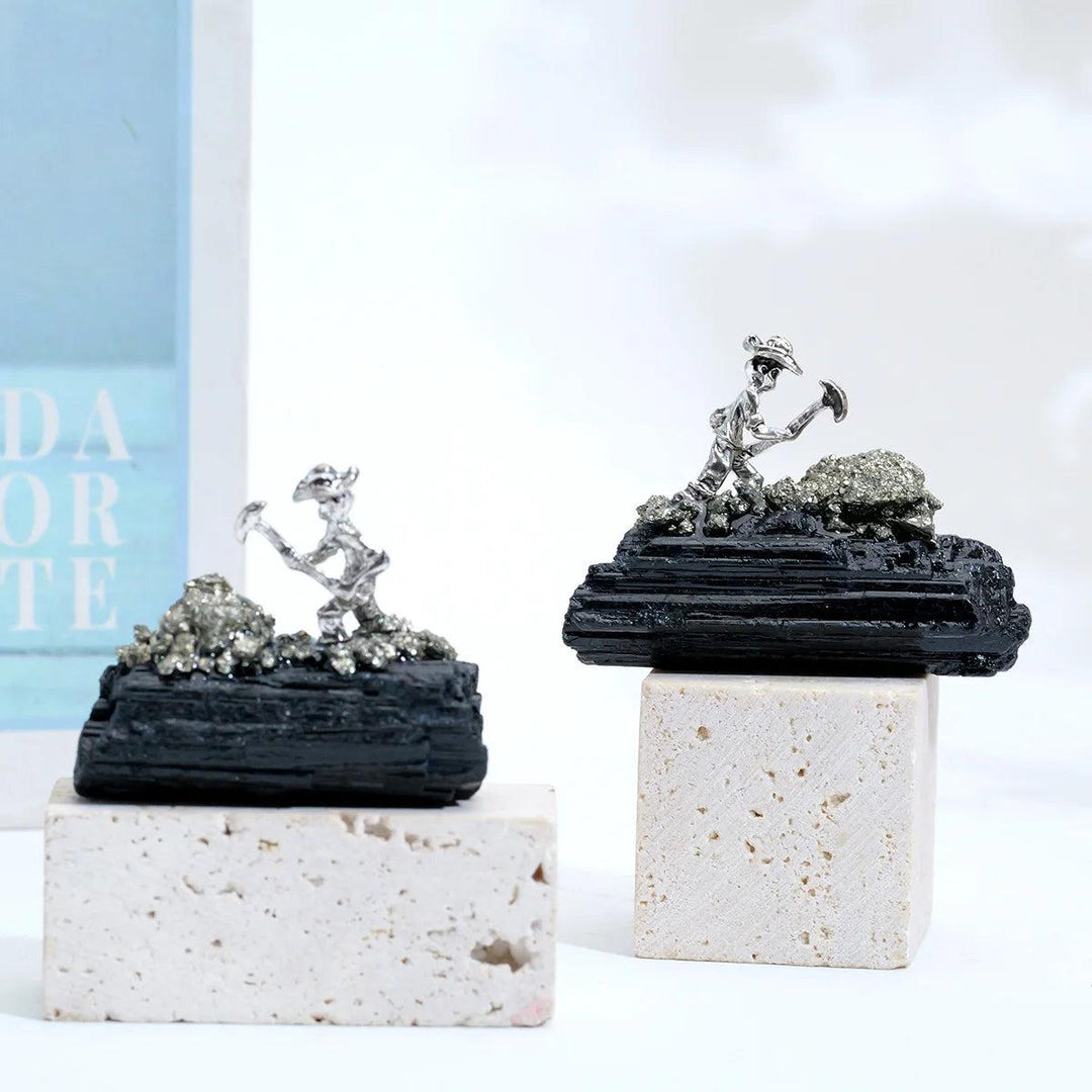 Raw black tourmaline specimen with a metal miner figurine for grounding, protection, and Root Chakra stability.