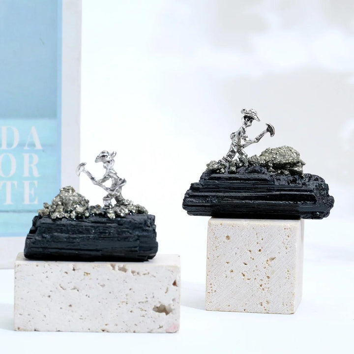 Raw black tourmaline specimen with a metal miner figurine for grounding, protection, and Root Chakra stability.