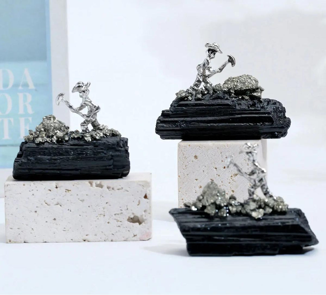 Raw black tourmaline specimen with a metal miner figure, featuring grounding columnar growth for root chakra protection.
