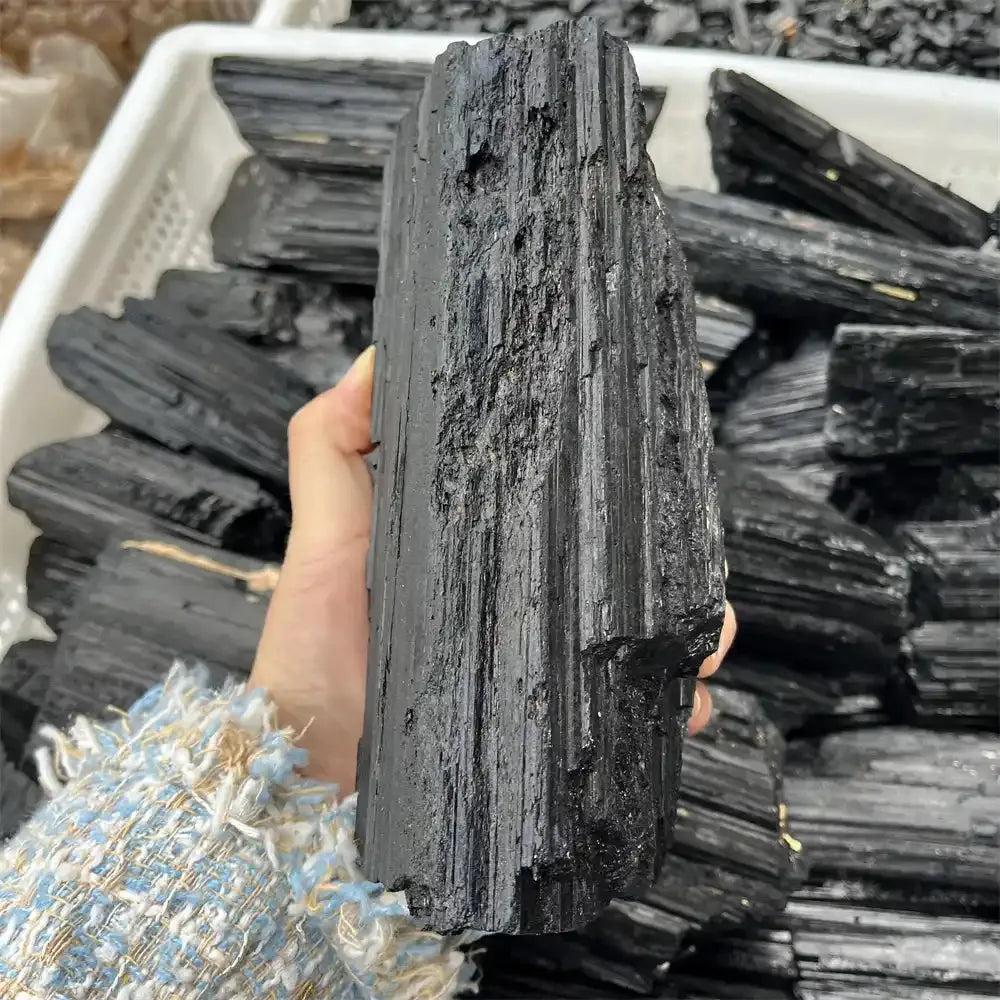 Handheld Black Tourmaline rough stone featuring deep black tones, natural lengthwise ridges, and grounding energy.