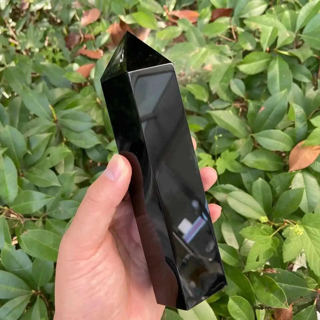 Hand-held glossy Black Tourmaline tower with a faceted point, perfect for Root chakra grounding and protective energy.