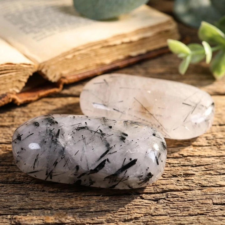 Polished black tourmaline in quartz palm stones for healing energy and home decor.
