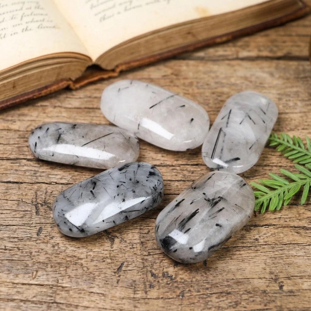Polished black tourmaline in quartz palm stones for healing and home decor.