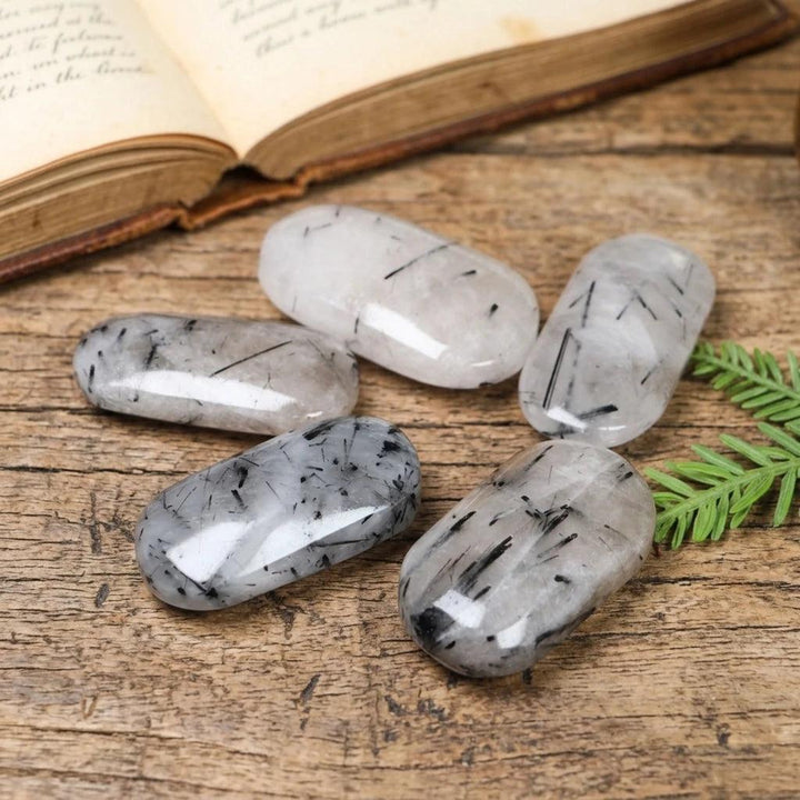 Polished black tourmaline in quartz palm stones for healing and home decor.