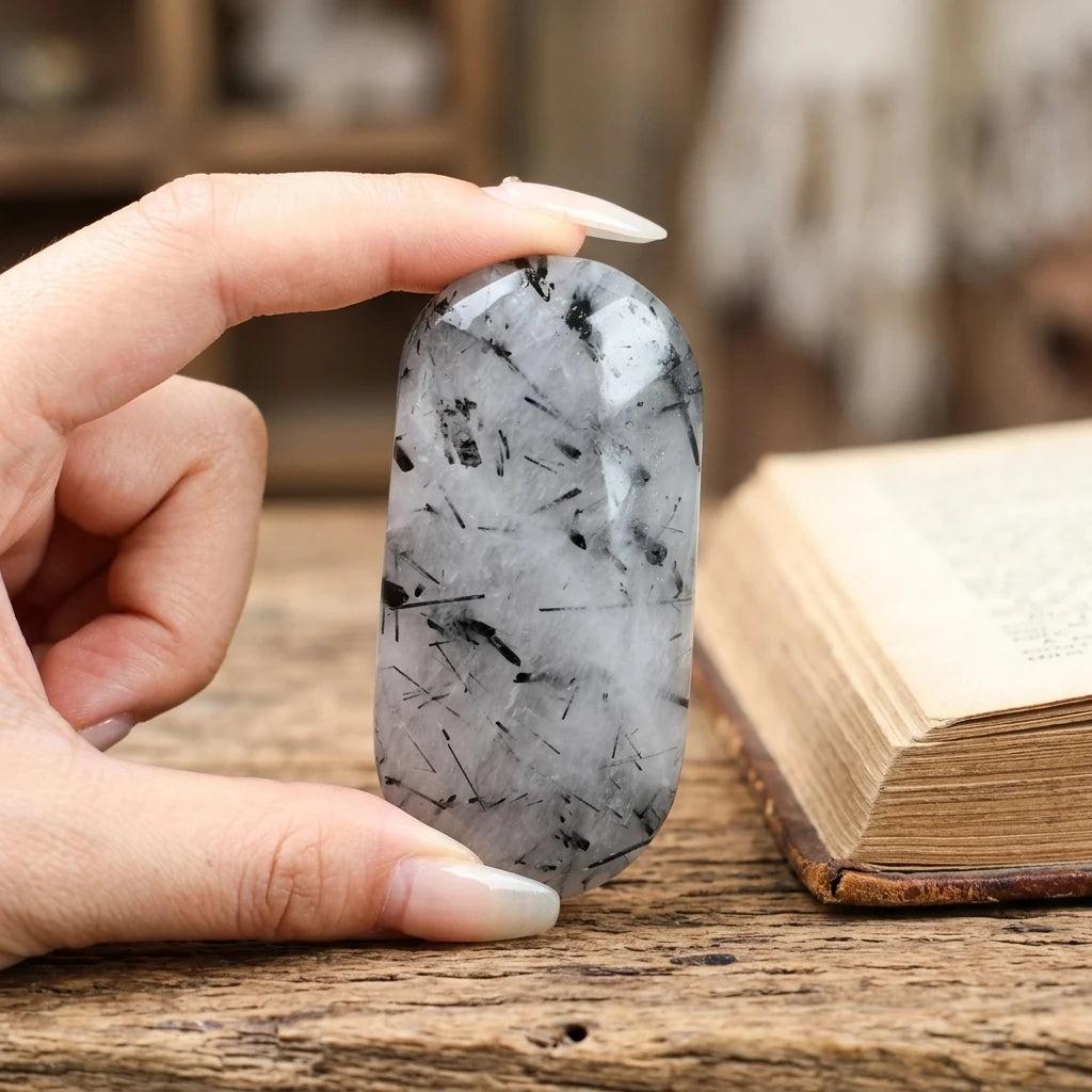 Polished black tourmaline rutilated quartz palm stone for healing energy and home decor.