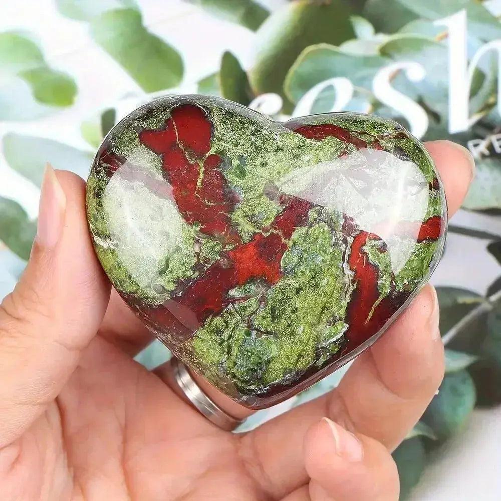 Polished Bloodstone heart crystal, vibrant green with deep red veins, held in a hand, promoting peace & tranquility.