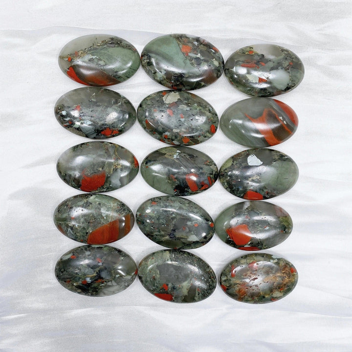 Polished bloodstone palm stones, dark green with vivid red spots, for healing and protection.