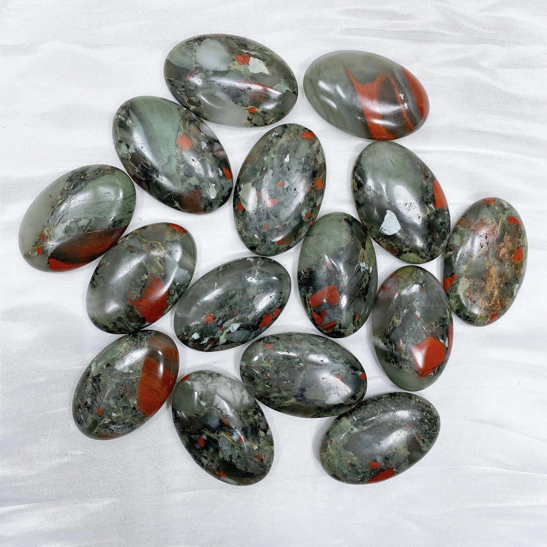 Polished Bloodstone palm stones, dark green with vivid red spots, for healing, protection, and grounding.