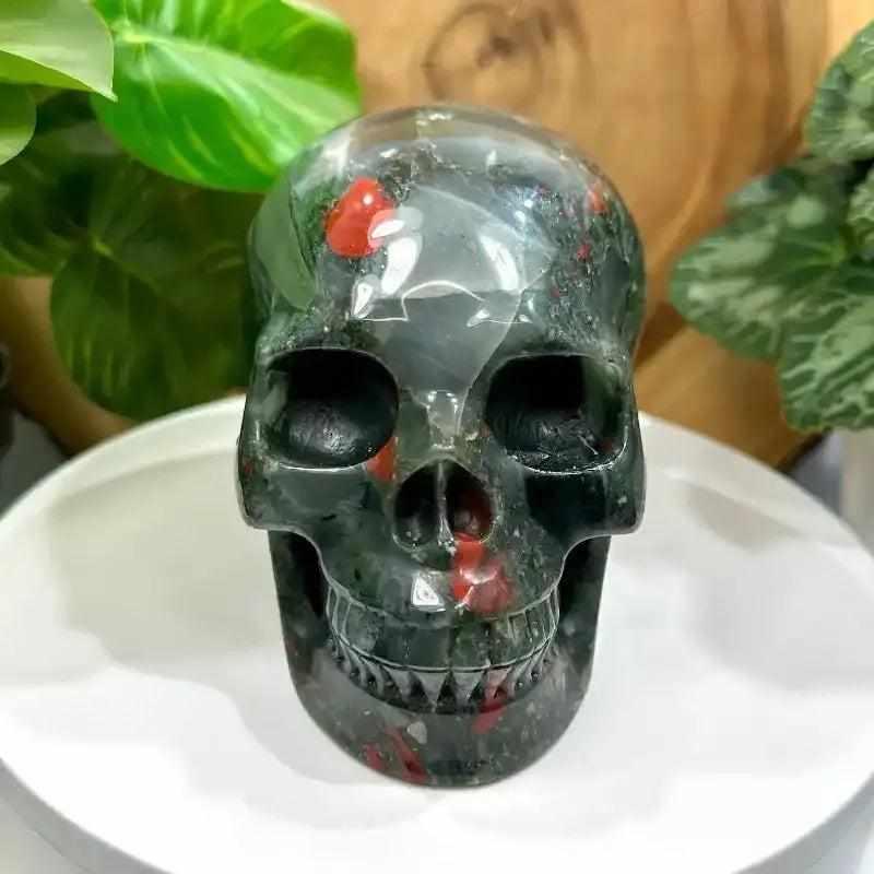 Hand-polished 40-50mm Bloodstone skull carving with deep green stone and vibrant red flecks for courage and vitality.