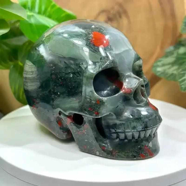 Hand-polished 40-50mm Bloodstone skull carving with deep green stone and vibrant red flecks for courage and vitality.