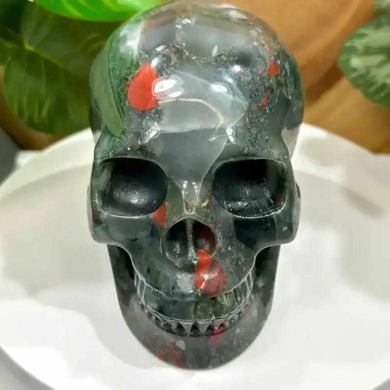 Hand-polished 40-50mm bloodstone skull carving with deep green stone and vibrant red flecks for courage and vitality.