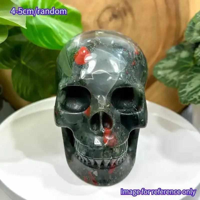 Hand-polished 40-50mm Bloodstone skull carving with deep green stone and vibrant red flecks for courage and vitality.