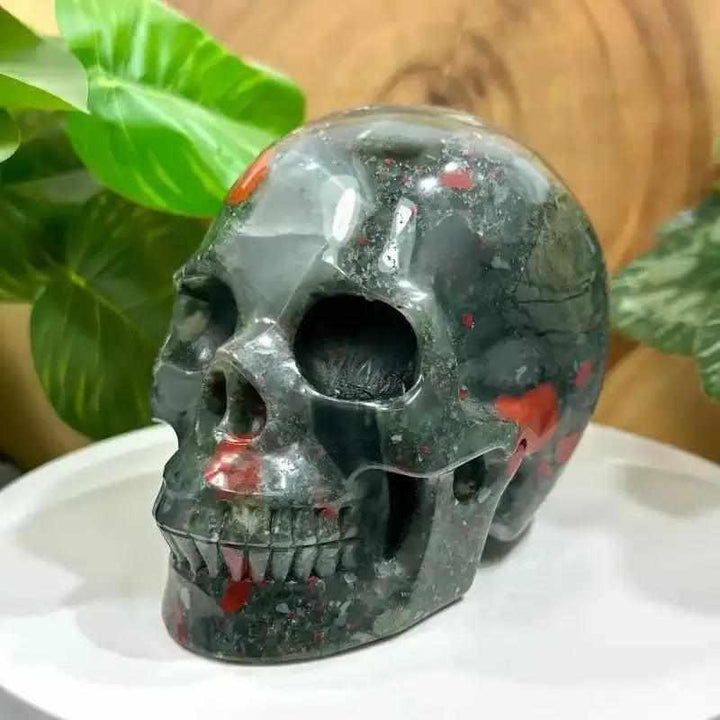 Hand-polished Bloodstone skull carving, 40-50mm, featuring deep green stone with bold red flecks for vitality and courage.