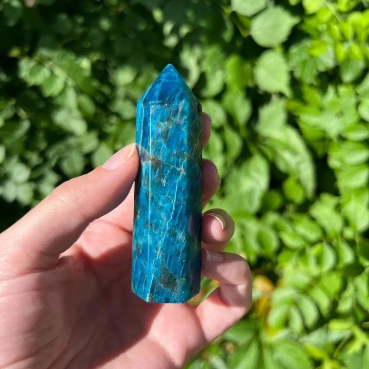 Vibrant blue apatite crystal tower point held in hand, showcasing natural healing stone details.