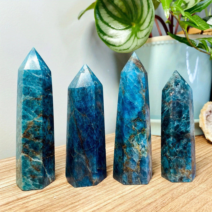 Four polished Blue Apatite crystal towers with vibrant teal and brown veins on a wooden surface.