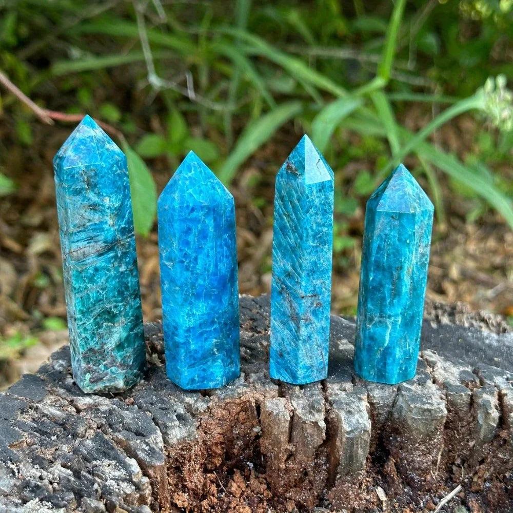 Vibrant blue apatite crystal towers on a rustic wood stump, perfect for healing and decor.