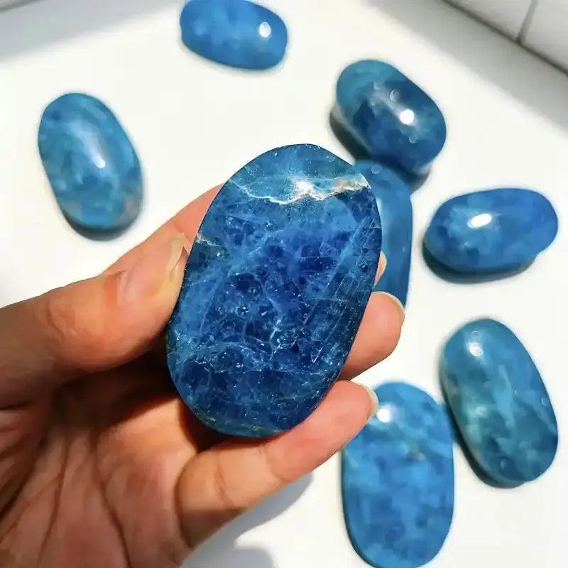 Handheld blue apatite palm stone with deep ocean hues and natural crystal textures, perfect for healing and home decor.