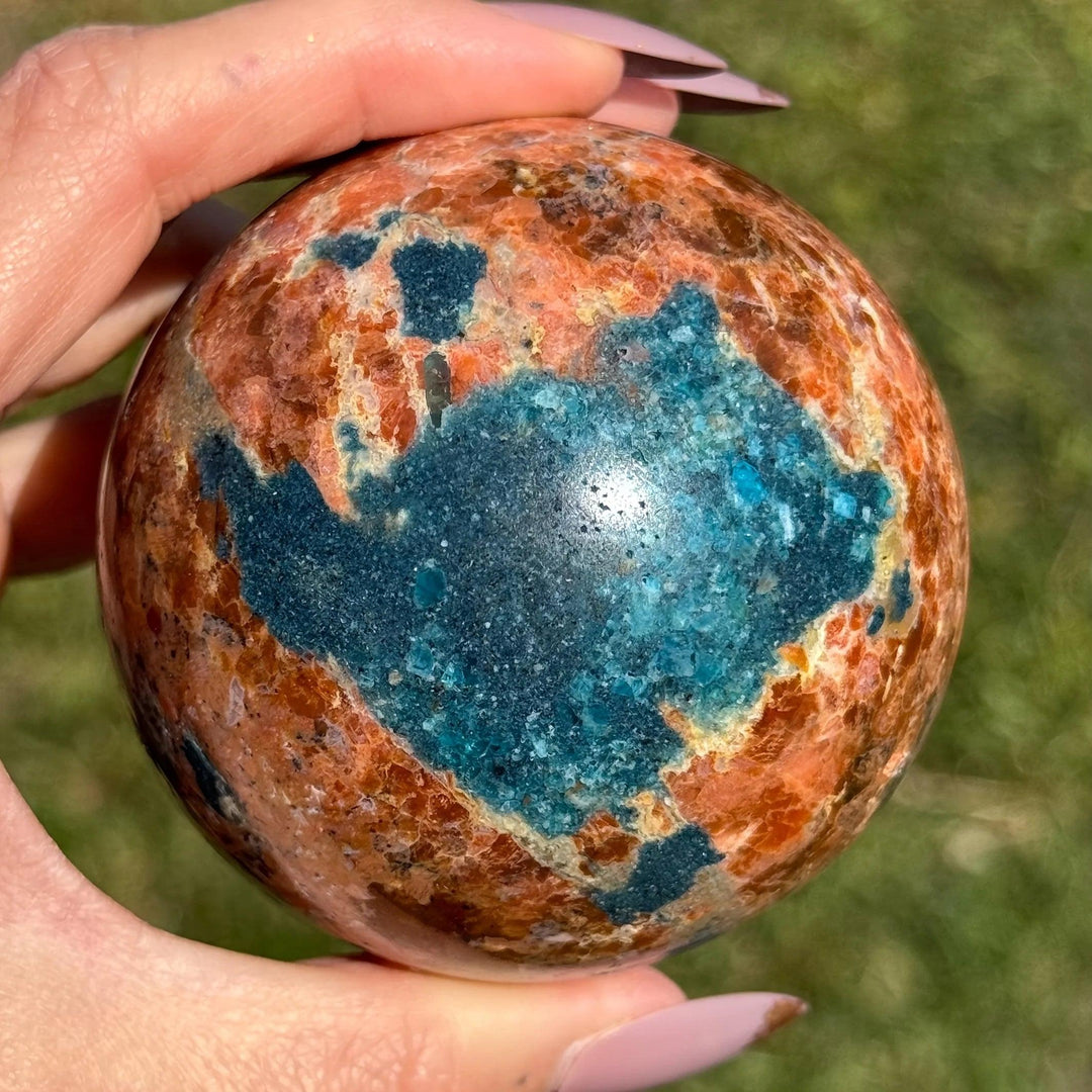Polished Blue Apatite Sunstone Crystal Sphere with vibrant orange and blue tones for energy and manifestation.