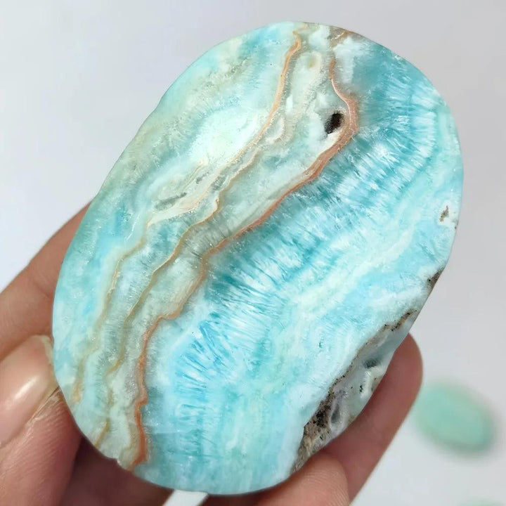 Polished Blue Aragonite palm stone with calming sky-blue hues and natural banding for emotional healing and tranquility.