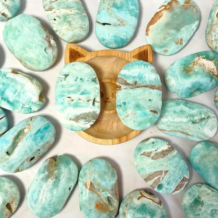 Polished blue aragonite palm stones in calming sky-blue and teal, perfect for anxiety relief and emotional healing.