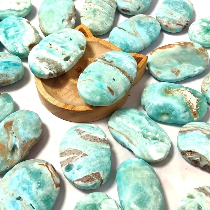 Polished blue aragonite palm stones in calming sky-blue and teal, perfect for anxiety relief and throat chakra healing.