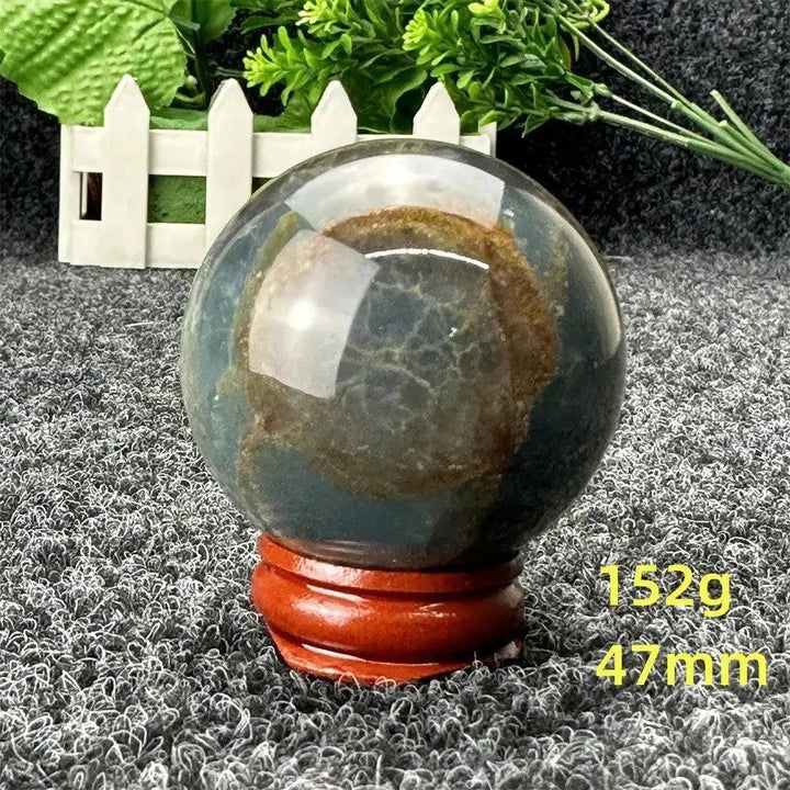 Blue Calcite Crystal Sphere: Polished, serene blue and brown sphere on a wooden stand, radiating calming energy for emotional healing.