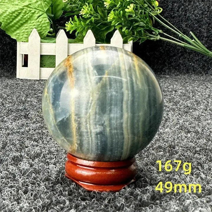 Stunning Blue Calcite Crystal Sphere, 49mm, with serene blue tones, natural patterns, and a wooden stand.