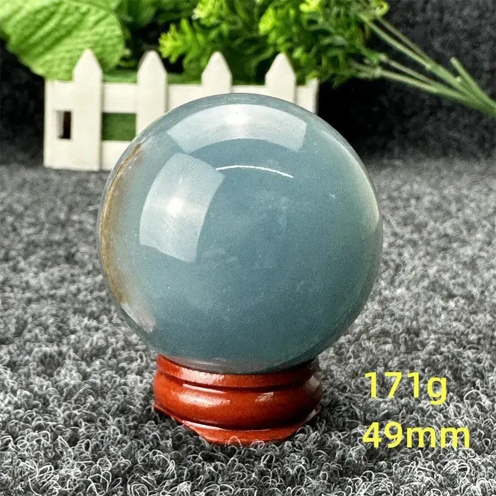 Stunning Blue Calcite Crystal Sphere, 49mm, 171g, on a wooden stand, radiating serene beauty and soothing energy.