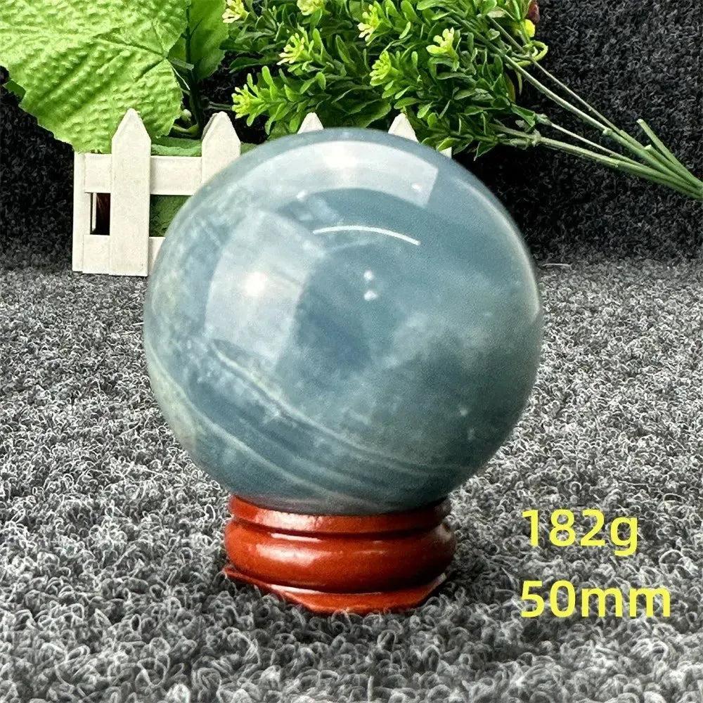 Stunning Blue Calcite Crystal Sphere, hand-polished with serene blue tones, on a wooden stand for peace and healing.