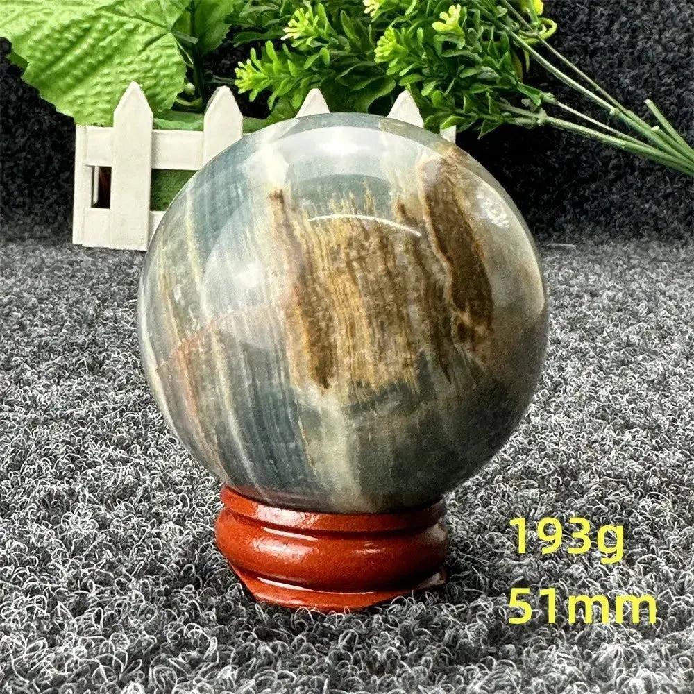 Blue Calcite Crystal Sphere: Hand-polished, serene blue and brown sphere on a wooden stand, promoting peace and communication.