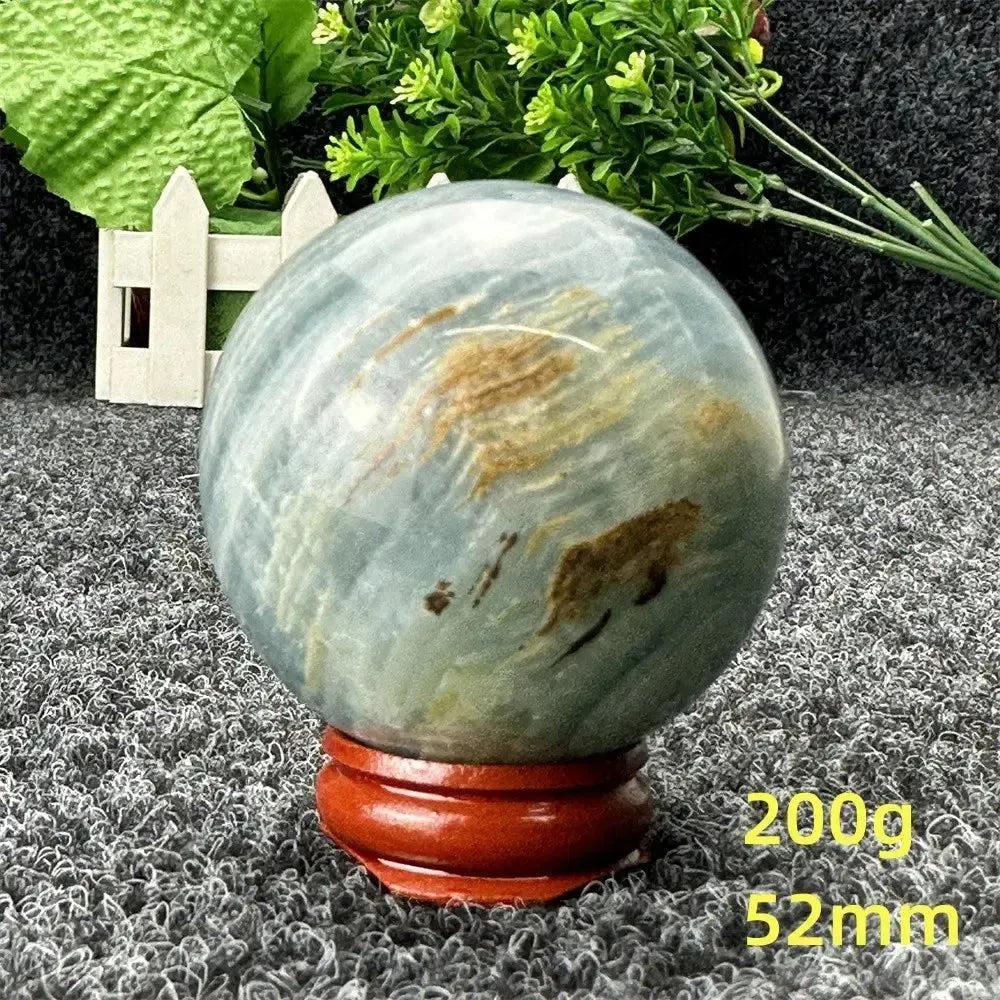 Stunning Blue Calcite Crystal Sphere, 52mm, with serene blue tones and natural brown patterns, on a wooden stand.