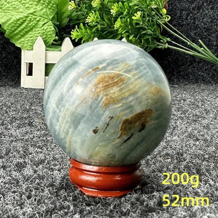 Stunning Blue Calcite Crystal Sphere, 52mm, with serene blue tones and natural brown patterns, on a wooden stand.
