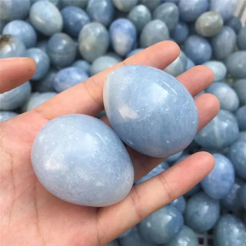 Two polished Blue Celestite crystal eggs, 40-50mm, held in a hand for peace and calm.