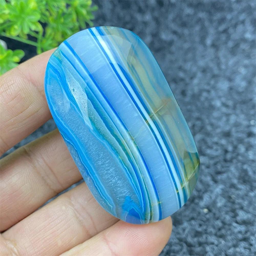 Hand-polished Blue Lace Agate palm stone with calming blue bands, perfect for soothing energy and home decor.