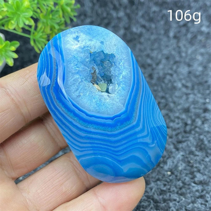 Polished 106g Blue Lace Agate palm stone featuring calming blue bands and a sparkling crystal geode center for healing.
