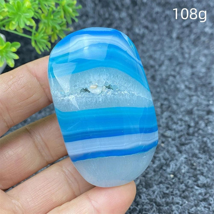 Polished 108g Blue Lace Agate palm stone featuring calming blue bands and a natural crystal center for healing decor.