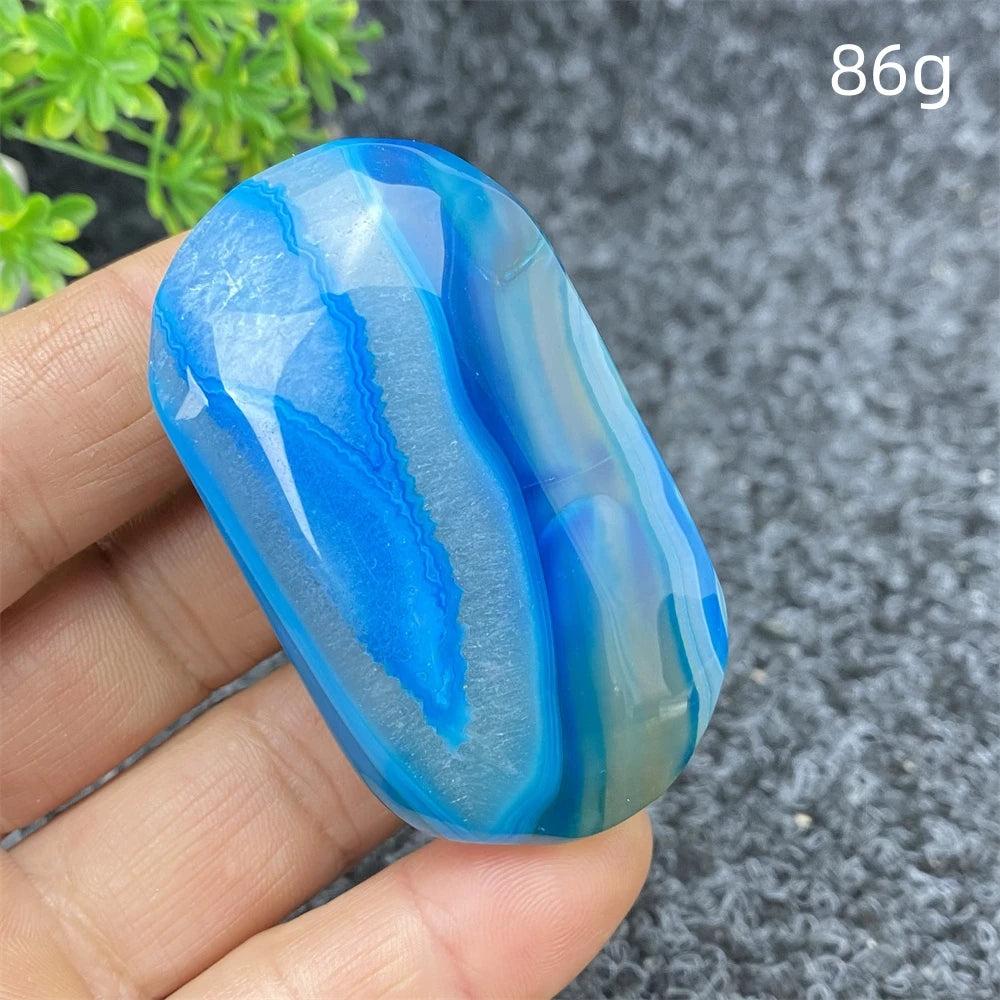 Polished 86g Blue Lace Agate palm stone featuring vibrant blue banding and a calming, natural crystal energy for healing.