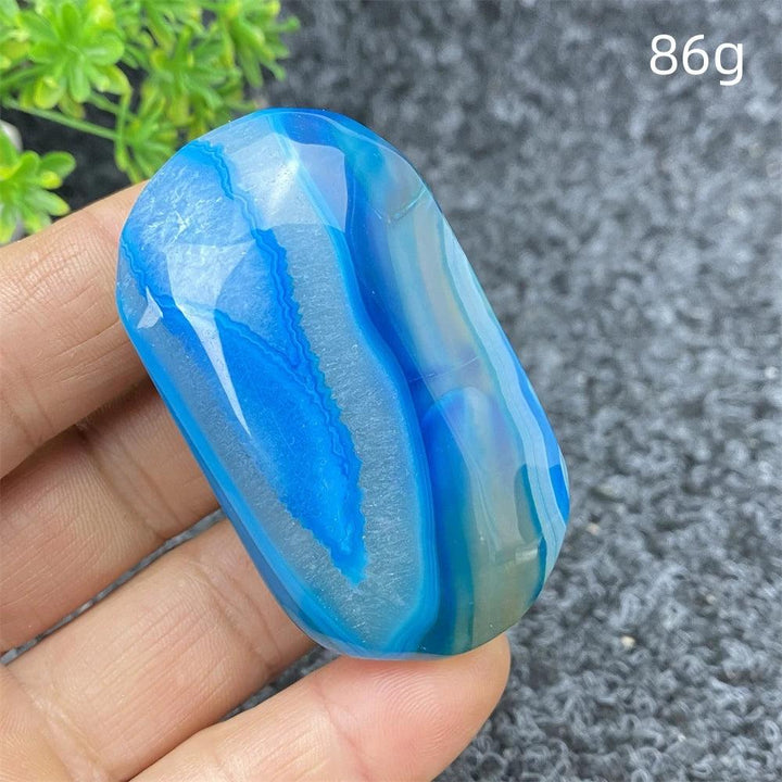 Polished 86g Blue Lace Agate palm stone featuring vibrant blue banding and a calming, natural crystal energy for healing.
