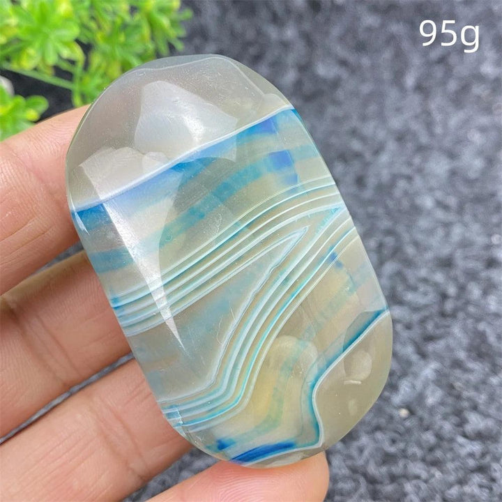 Polished 95g Blue Lace Agate palm stone featuring calming blue bands for soothing energy and beautiful home decor.
