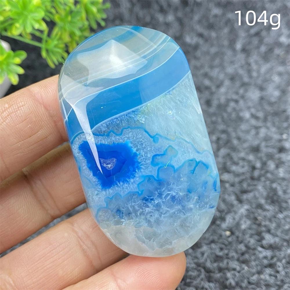 Polished 104g Blue Lace Agate palm stone with calming blue bands and crystal geode center for healing and home decor.