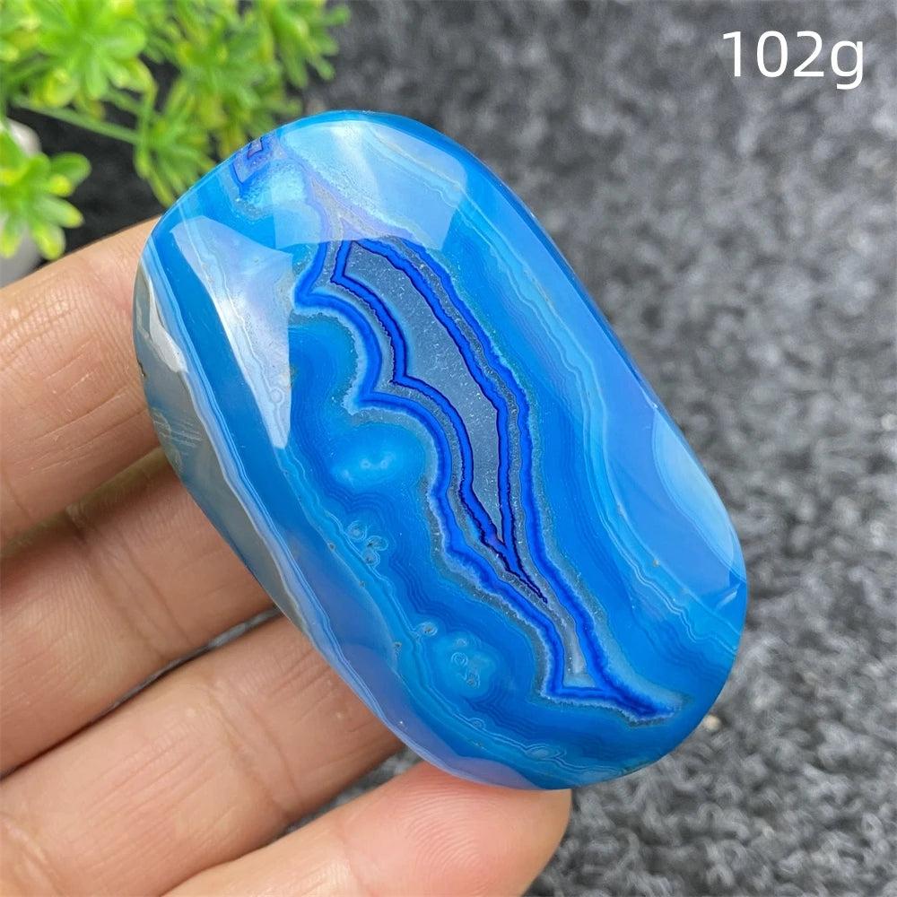 Polished 102g Blue Lace Agate palm stone featuring calming blue banded patterns, perfect for healing and home decor.
