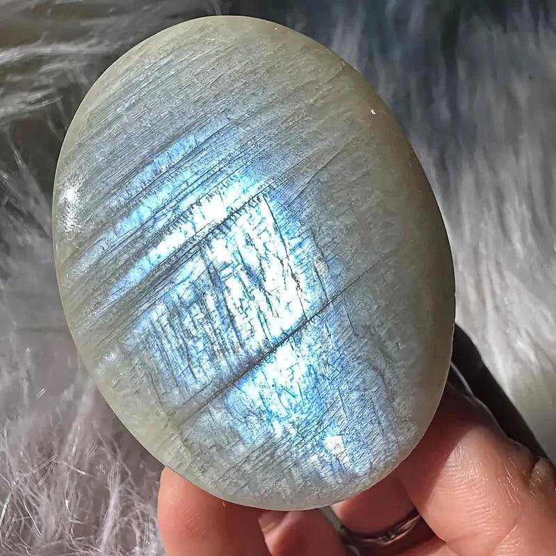 Polished Blue Moonstone oval palm stone featuring a radiant blue-white adularescence shimmer for meditative healing.