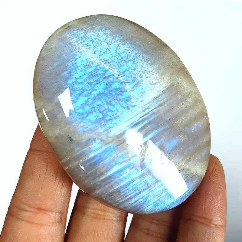 Polished blue moonstone oval palm stone featuring a mesmerizing blue-white adularescence shimmer for meditation.