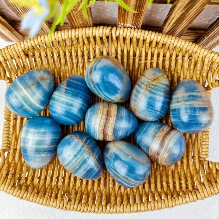 Blue Onyx Crystal Polished Eggs for calm and clarity, with cool blue and brown bands, in a woven basket.