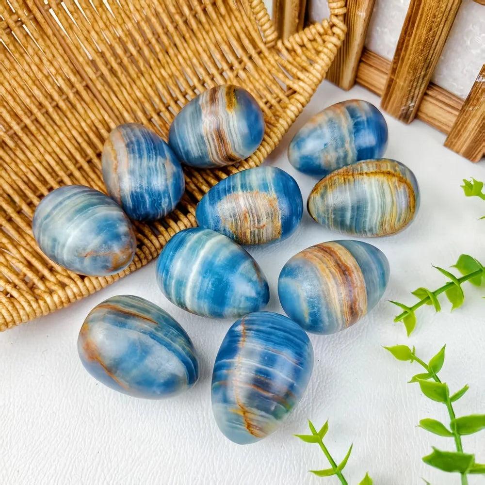 Polished Blue Onyx crystal eggs with natural blue, brown, and white banding, resting on a woven basket.