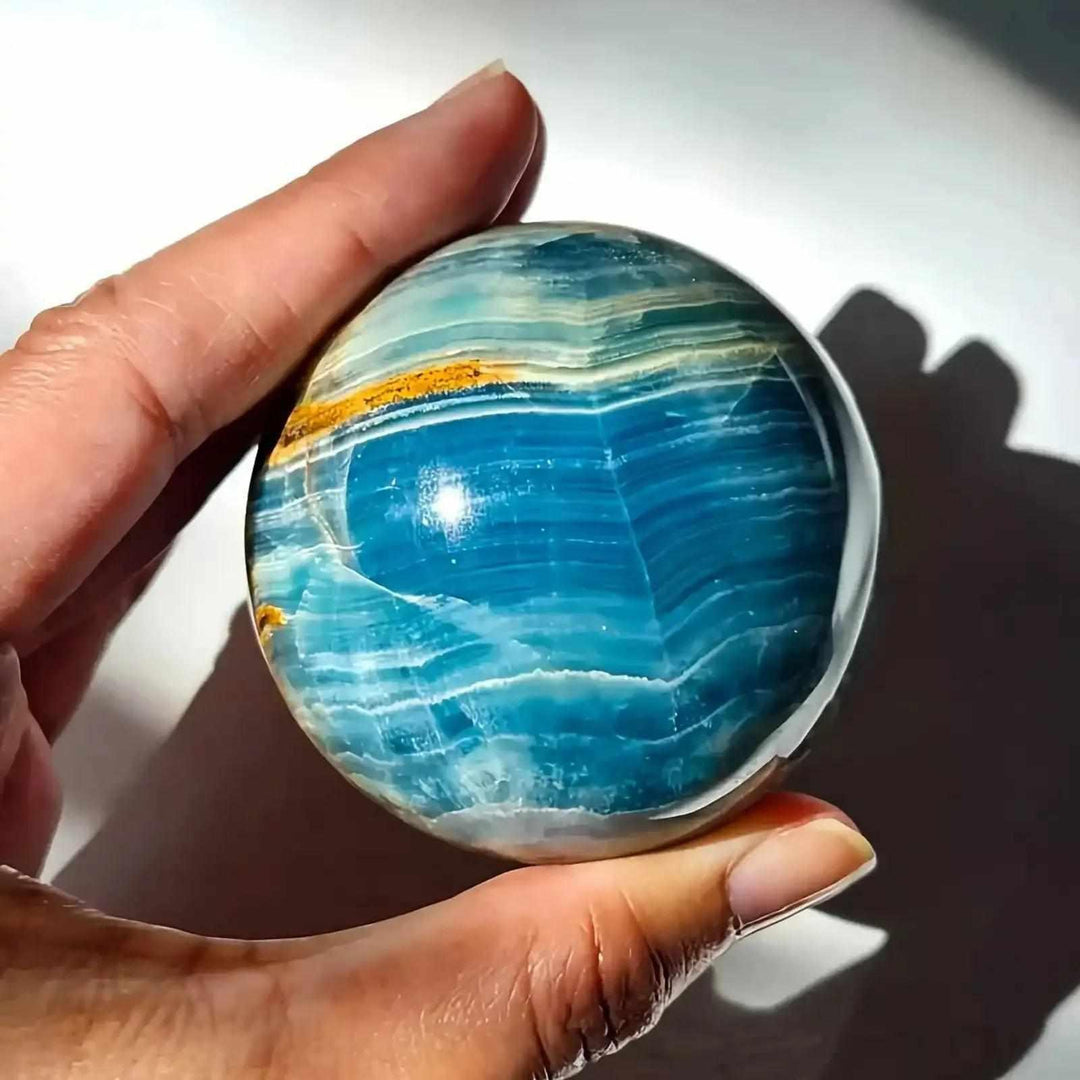 Hand-polished Blue Onyx sphere featuring vibrant blue layered bands for Throat and Third Eye chakra meditation.