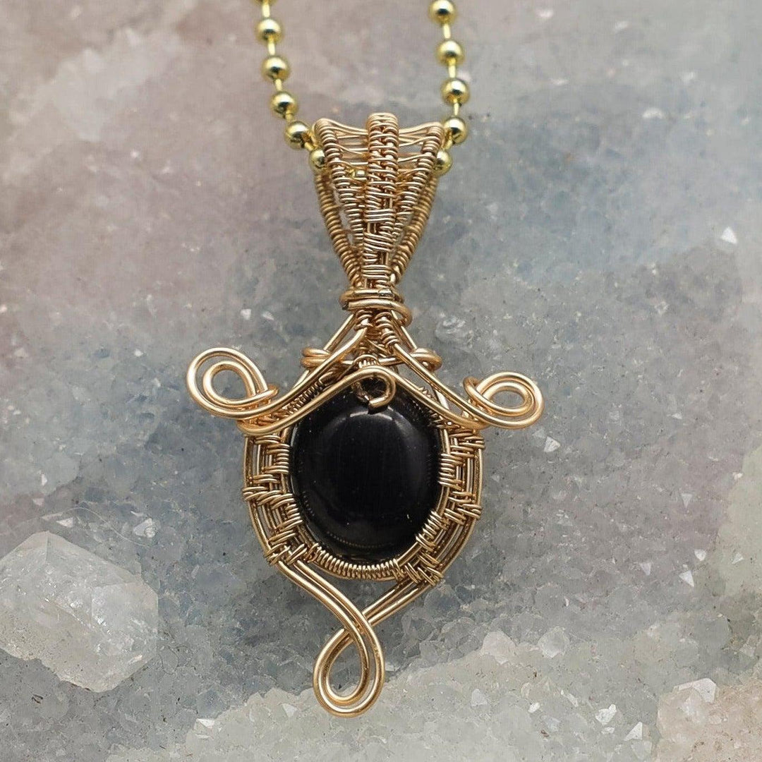 Handcrafted 2-inch black onyx wire-wrapped pendant in healing copper, promoting confidence and positive energy.
