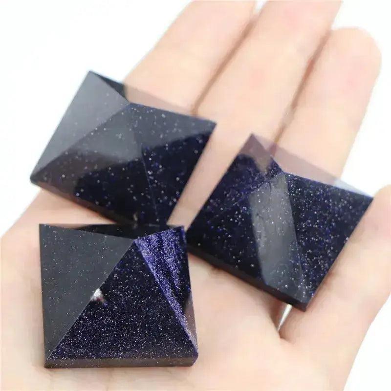 Three shimmering blue sandstone crystal pyramids with golden flecks, held in a palm. Crystal Destiny.